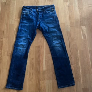 Replay Waitom blå jeans regular fit - Säljer ett par Replay Waitom jeans i klassisk blå tvätt med snygga slitningar. Regular fit med raka ben och fem fickor. Jeansen har läderpatch bak i midjan och tydliga Replay-detaljer. Perfekta för dig som gillar en tidlös och avslappnad stil.       Ingen idé att fråga efter bilder när jag har dem på mig dem är för små.