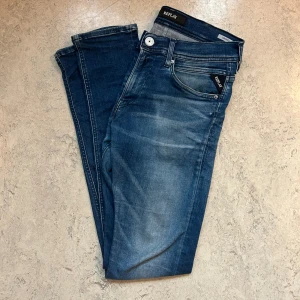 Blå Replay jeans - Snygga blå jeans från Replay i storlek W30 L32, med klassisk femficksdesign. Modellen har raka ben och normal passform och detaljerade bakfickor. Perfekta för dig som gillar stilrena och bekväma jeans.