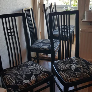 Fyra svarta stolar  - Bilderna visar fyra eleganta matstolar med svart trästomme och mönstrad sits i svart och grått med bladmönster. Stolarna har en modern design med vertikala ribbor i ryggen. Skicket ser bra ut, med endast mindre tecken på normalt slitage. Perfekt för kök eller matsal. Vi säljer en stol för 190kr! 
