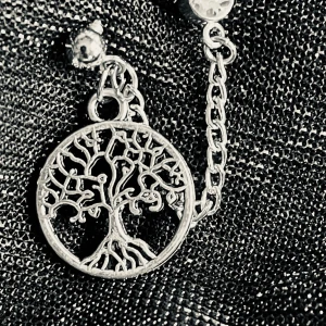By prisförslag- 1 st Silverfärgat örhänge med livets träd - Unikt örhänge i silverfärg med en rund berlock som föreställer livets träd. Hängs på en tunn kedja och har en gnistrande sten upptill. Perfekt för dig som gillar detaljer och symbolik i dina smycken.