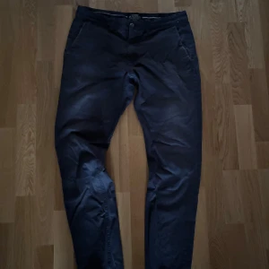 Mörkblå chinos från Bondelid - Snygga mörkblå chinos från Bondelid med klassisk passform. Byxorna har sidfickor, bakfickor med diskret broderad logga och är tillverkade i mjuk bomull. Storlek 33,32. Har inga defekter. 