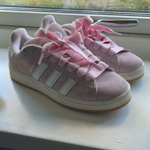 Adidas Campus rosa sneakers strl 38 - Säljer ett par Adidas Campus sneakers i ljusrosa mocka med vita detaljer och breda rosa skosnören. Klassisk modell med tre vita ränder på sidan och gummisula.❤️
