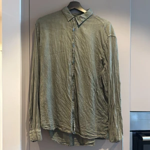Olivgrön linneskjorta med knappar Ljung  - Snygg olivgrön skjorta från Ljung i linne med klassisk krage och knäppning framtill. Skjortan har lång ärm och en avslappnad passform, perfekt för en chill och stilren look. Materialet är svalt och ger en naturlig vibe. Nypris cirka 1000kr. Behövs bara strykas, annars typ nyskick 