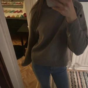 Brun stickad polotröja HM - Mysig ljus brun stickad polotröja med ribbade muddar och hög krage. Tröjan har en loose passform och är perfekt för kyligare dagar. Använd ändadt väldigt få gånger 