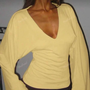 Gul långärmad topp med v-ringning - Trendig gul långärmad topp med djup v-ringning och figurnära passform. Toppen har vida ärmar och är tillverkad i ett mjukt material som sitter snyggt på kroppen. Perfekt för dig som vill sticka ut med en färgglad och stilren look.helt oanvänd 