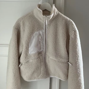  teddyjacka från NLY Trend strl. 36 - Vit teddyjacka/pilejacka från Nelly i storlek 36. Två fickor och stängs med dragkedja. En väldigt liten fläck på bröstfickan samt lite smutsig vid kragen, se sista bilderna.