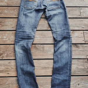Nudie Jeans  - Säljer ett par nudie jeans med snygga slitningar och tvättade detaljer. Jeansen har klassisk femficksdesign och smal passform hela vägen ner. Perfekta för dig som gillar en avslappnad look och vill ha ett par jeans som sticker ut lite extra. Tveka inte att fråga vid minsta intresse! Pris går att diskuteras vid snabb affär!