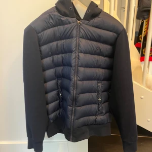 Mörkblå pufferjacka från Polo Ralph Lauren - Snygg mörkblå Cardigan från Polo Ralph Lauren med huva och dragkedja. Priset är inte hugget i sten. 