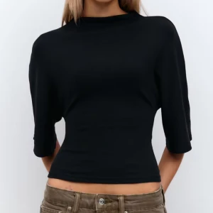 Svart omlottopp med knyt i ryggen - Säljer en svart omlottopp med halvlånga ärmar och snygg knytning i ryggen. Toppen är croppad och har en stilren, figurnära passform. Perfekt för dig som gillar minimalistisk stil med en twist. Materialet känns mjukt och följsamt mot kroppen. Använd 2 gånger. Storlek xs men kan användas också som S. Pris kan diskuteras.