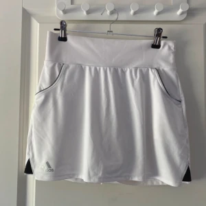 Vit sportig kjol från Adidas - Väldigt populär och många är intresserade. Säljs snabbt, så skynda att köpa. Först till kvarn!  Superfin kjol med inbyggda short och fickor på sidorna. Ungdomsstorlek L men passar damstorlek XS.