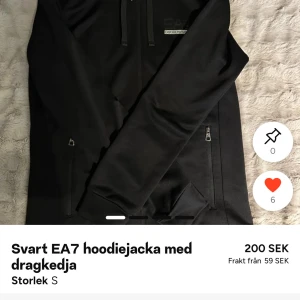 Svart hoodiejacka från EA7 Emporio Armani - Svart hoodiejacka från EA7 Emporio Armani med hel dragkedja framtill, huva med snören och två fickor med dragkedja. Jackan har en clean look och är tillverkad i mjukt syntetmaterial. Perfekt för dig som gillar stilren streetwear. Kan ha några defekter på framsidan men inte något som sticker ut.