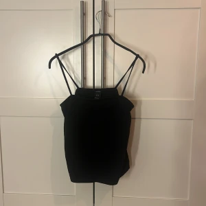 Svart linnetopp från Lindex - Svart linnetopp från Lindex i storlek M. Toppen har smala axelband och en enkel, stilren design med rak passform. Materialet känns lätt och bekvämt, perfekt för att matcha med jeans eller kjol. Snygg och enkel att styla för en cool look.