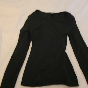 Svart långärmad tröja  - En stilren svart långärmad tröja från Amisu i storlek S. Tröjan har en klassisk rund halsringning och är figurnära i modellen, perfekt att matcha med jeans eller kjol. Enkel och snygg bas i garderoben.