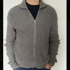 Grå stickad kofta med dragkedja Massimo Dutti - Riktigt skön grå stickad kofta med dragkedja framtill. Passar perfekt nu till hösten. Säljer för att jag inte använder den längre.