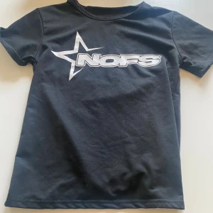 Svart NOFS t-shirt med stjärntryck - Svart t-shirt från NOFS med ett stort vitt stjärntryck och logga på bröstet. Den är oanvänd och helt ny. Passar inte mig därför säljer jag den.Klassisk rund halsringning och korta ärmar. Tillverkad i mjuk bomull för en skön känsla. Perfekt för dig som gillar streetwear och enkel stil.