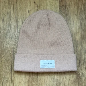 Rosa stickad mössa från Lager 157 - Snygg rosa stickad mössa från Lager 157 med uppvikt kant och en vit patch framtill med texten 'Everyday Beanie'. Tillverkad i mjuk och stretchig akryl, perfekt för kyliga dagar. Enkel och stilren design som passar till det mesta.