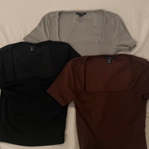 Tre toppar med fyrkantig hals från New Yorker  - Säljer tre stilrena toppar från Amisu, alla är i storlek M. En svart, en grå och en brun, alla med kort ärm och fyrkantig halsringning. Inte använda, förutom den gråa har jag använt 1-2 ggr. 1 för 80