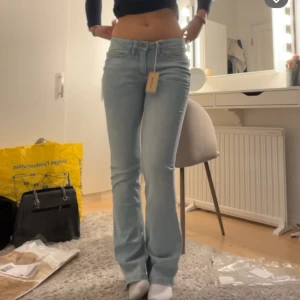 Ljusblå bootcut jeans John Baner - Snygga ljusblå jeans från John Baner med klassisk bootcut-modell. Jeansen har fem fickor, bälteshällor och coola sömdetaljer på bakfickorna. Tillverkade i mjukt denimtyg som sitter skönt och ger en avslappnad vibe.