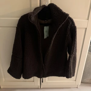 Mörkbrun teddyjacka från Gina tricot  - Populära teddy jackan från Gina tricot, säljes då jag hellre vill ha den i S. Helt ny med lappen kvar.