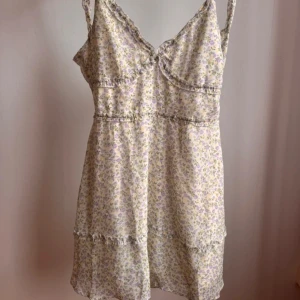 Blommig klänning - Söt blommig klänning från HM Divided. Öppen rygg med knytning bak. Dold dragkedja på vänstersida. Storlek 42, dock liten i storleken och passar mig som är en 38a. Endast testat, prislappen kvar.
