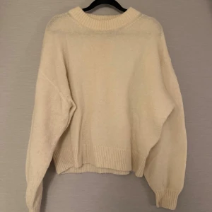 Oversized beige stickad tröja - Mysig oversized stickad tröja i vitt från  & other stories, med bred ribbad kant vid hals, ärmslut och nederkant. Tröjan har lång ärm och en enkel, clean look som är lätt att matcha med jeans eller kjol. 