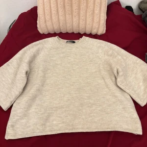 Beige stickad tröja från Monki - Säljer en beige stickad tröja från Monki med rund hals och avslappnad passform. Tröjan har långa ärmar och är perfekt för kyliga dagar. Enkel och stilren design som är lätt att matcha med olika outfits.