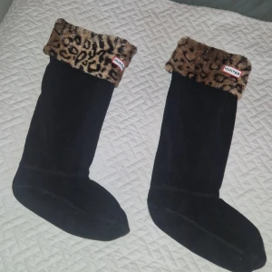 Hunter stövelstrumpor - Knappt använda Hunter-stövelstrumpor som är specifikt utformade för att användas med Hunters gummistövlar, särskilt de höga modellerna. De är tillverkade av mjuk fleece med en dekorativ fuskpäls-manschett med leopardmönster. Manschetten viks över kanten på stöveln för att visa Hunter-logotypen. Ger extra värme och bekvämlighet samt så är det fint. 