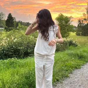 Vit broderad blus med spetsdetalj - Säljer en söt vit blus i bomull med broderade hålmönster och en fin spetsdetalj över bröstet. Blusen har volangärmar och en luftig, avslappnad passform. Perfekt för varma dagar och ger en romantisk vibe till din outfit.