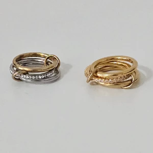 Två coola ringar i guld och silver - Säljer två snygga ringar med flera sammanlänkade ringar i både guld och silverfärg. Storlek 5 på båda. Köpta för 259 kr styck.