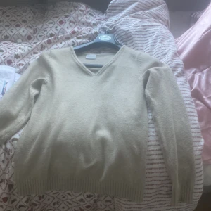 Beige v-ringad stickad tröja från Vila - Mysig beige stickad tröja från Vila med v-ringning och långa ärmar. Perfekt för lager-på-lager och chill dagar. Ribbstickade muddar vid ärmslut och nederkant ger en snygg och enkel look.