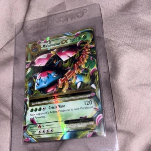 M Venusaur EX - Cool och glittrande Pokémon-samlarbild med M Venusaur EX! Perfekt för dig som älskar Pokémon och vill ha en unik och kraftfull kort till din samling. Kortet är skyddat i plastfodral och har snyggt motiv med starka attacker.