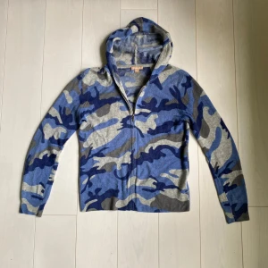 Blå camo kashmir hoodie från Kier & J - Säljer en snygg blå camouflagemönstrad hoodie från Kier & J i 100% kashmir. Tröjan har dragkedja och långa ärmar, perfekt för en avslappnad stil. Den är mjuk och bekväm, idealisk för kyligare dagar. Lite många småhål överallt men inget som syns med något överplagg när den används. Galet fet men hade rekommenderat att sy. Nypris runt 2600