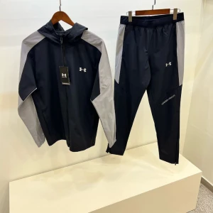 Tracksuit från Under Armour - Svart tracksuit från Under Armour med grå kontrastpaneler på ärmarna och huva. 