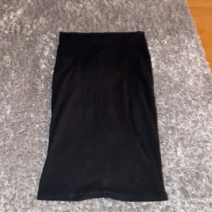 Svart långkjol från Cubus - Svart långkjol från Cubus i mjukt bomullsmaterial. Kjolen har en rak och enkel design med resår i midjan för skön passform. Perfekt för dig som gillar stilrena och minimalistiska plagg. Passar dig som vill ha en klassisk svart kjol i garderoben.