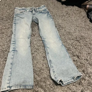 Bootcut jeans ljusblå.  - Storlek 146. Snygga ljusblå jeans från Hm med bootcut passform och klassisk femficksdesign. Jeansen har slitna detaljer, dubbla knappar i midjan och dragkedja. Använd unngfär 4 gånger