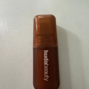 Huda Beauty Blush Filter flytande rouge färg Latte - Flytande rouge från Huda Beauty i en snygg brun plastförpackning med texten 'Blush Filter'. Perfekt för att ge kinderna en fräsch och naturlig färg. Smidig att applicera och lätt att ta med i väskan.