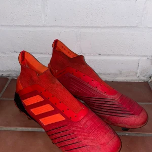 Adidas Predator röda fotbollsskor - Säljer ett par Adidas Predator Elite fotbollsskor, röda med svarta och orange detaljer. Använda i ungefär en halv säsong, max.