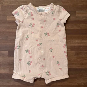 Ljusrosa romper med smultron - Supersöt ljusrosa romper med smultron från H&M i storlek 62 (2-4mån). Använt fåtal gånger och i extremt fint skick utan anmärkningar.