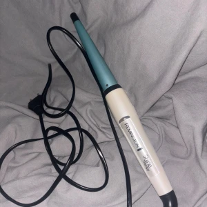 Locktång  - Remington Shine Therapy Curling Wand med keramisk beläggning för skonsam styling.13-25 mm och har   Konisk design med snabb uppvärmning, temperaturinställningar upp till 210°C.