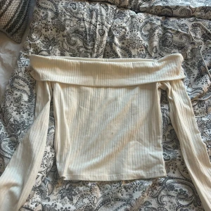 Offshoulder ribbad topp från H&M Divided S - Säljer en ljusvit offshoulder topp från H&M Divided i storlek S. Toppen är ribbad och har långa ärmar, perfekt för en trendig och stilren look. Materialet är mjukt och stretchigt, vilket gör den bekväm att bära.