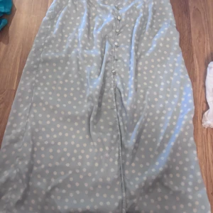 Ljusblå blommig långkjol från Pieces - Supersöt ljusblå långkjol från Pieces med små vita blommor och knappar framtill. Kjolen har en flowy passform och är perfekt för vår och sommar. Materialet känns lätt och luftigt.