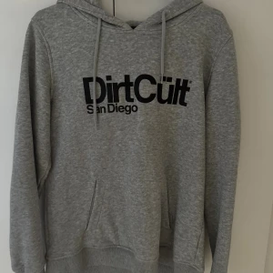  hoodie DirtCult  - Grå hoodie från DirtCult San Diego med svart tryck framtill. Storlek L men är som S eller M