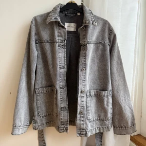 Grå jeansjacka med bälte Carin Wester - Säljer en grå jeansjacka från Carin Wester i storlek 36. Jackan har klassisk krage, två stora fickor framtill, knappar och ett snyggt bälte i midjan. Perfekt oversized look med lång ärm och cool tvättad finish. Använd 1 gång.
