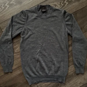 Grå  från Oscar Jacobson - Säljer en stilren grå tröja från Oscar Jacobson. Klassisk rund halsringning och ribbade muddar vid ärmslut och nederkant. Perfekt för lager på lager och funkar året runt. Enkel att matcha med allt i garderoben.