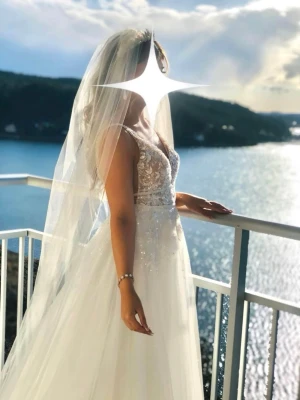 Vit lång bröllopsklänning med spets - Drömmig vit bröllopsklänning med v-ringad urringning, ärmlös design och vackra spetsdetaljer. Den är i flera lager tunn tyll som ger ett svävande intryck. Spetsen har broderade dekorationer och pärlor som glittrar lätt. Perfekt för dig som vill känna dig som en prinsessa. Klänning köptes för 15000 på Johans Högtidskläder i Göteborg säljs för 7499. Slöjan köptes separat på samma plats 499 kr extra om man vill ha med den, hör av vid frågor eller intresse! Klänningen har endast används en gång!