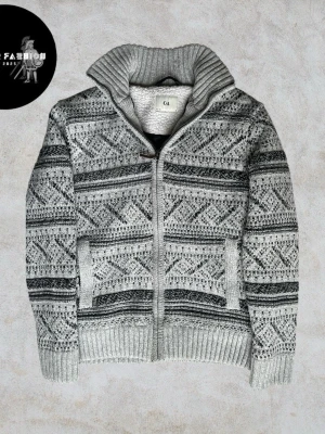 Stickad och fodrad cardigan jacka/ kofta - Grå stickad cardigan kofta med mönstrat yttre och quiltat svart foder på insidan. Hel dragkedja framtill och hög krage med mjuk fleece på insidan som ger extra värme. Skicket är nästintill ny utan defekter och knappt använd. Strl S. Hör av dig för mått!                                                               Nypris okänt liknande säljs för 500-700kr| Vårt pris 599 kr. Alla följare får rabatt – följ!