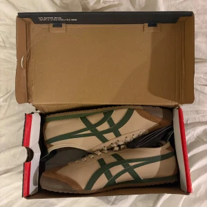 Onitsuka Tiger skor - Säljer ett par beige Onitsuka Tiger sneakers i modellen mexico 66 i beige/grön färg! Helt nya, hör av er vid intresse!