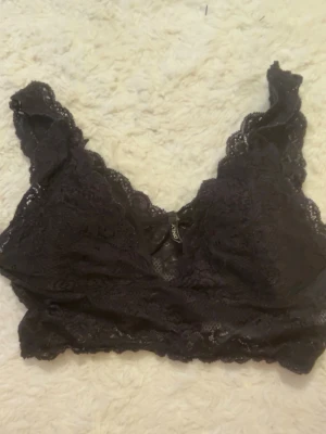 Svart spetsig topp  -  en svart topp med spets och breda axelband. Toppen har bra stretch i och mjukt tyg och ilägg i vid brösten.