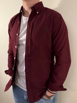 Vinröd Ralph Lauren skjorta - En snygg polo skjorta som passar till alla tillställningar! Framförallt under vinterhalvåret när du ska på exempelvis middag eller bara klä upp dig lite extra. Passform: Slim fit Storlek👔: S Nypris💰: ca 1299 kr