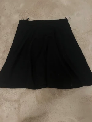 Svart volang kjol  - Enkel och stilren svart volantkjol med lätt utställd passform. Materialet känns mjukt. Använd knappt 3 gånger, säljer för att den inte kommer till användning.